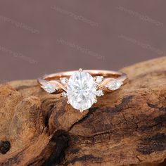 an engagement ring with three pear shaped diamonds on top of a piece of drift wood