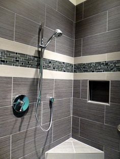 a walk in shower sitting next to a tiled bathroom wall with gray and white tiles