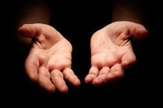 two hands reaching out towards each other with their palms spread wide in the air against a black background