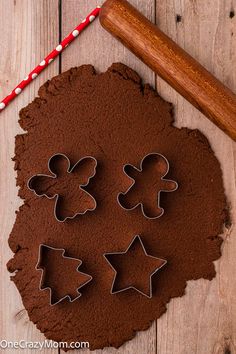 cookie cutters shaped to look like christmas cookies on top of a wooden table next to a rolling pin