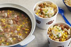 three bowls filled with soup next to two spoons