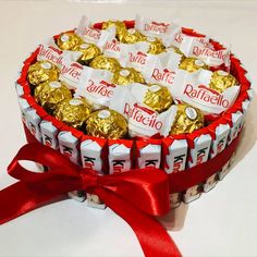 a box filled with lots of chocolates wrapped in red and white ribbon on top of a table