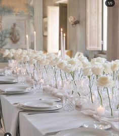 a long table is set with white roses and candles for a formal dinner or reception