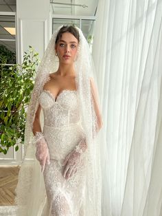 a woman in a wedding dress and veil posing for the camera with her hands on her hips