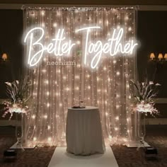 a lighted sign that says better together on the side of a stage with flowers and candles