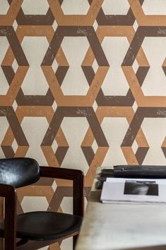 two chairs and a table in front of a wall with geometric designs on it,