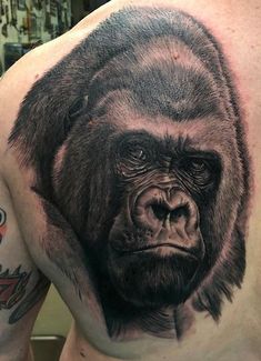 a man with a big gorilla tattoo on his chest and shoulder is looking at the camera