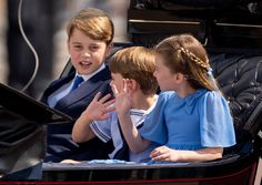 three children sitting in the back of a carriage waving to someone on the other side