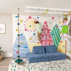 two children climbing up the side of a wall in a living room with blue couches