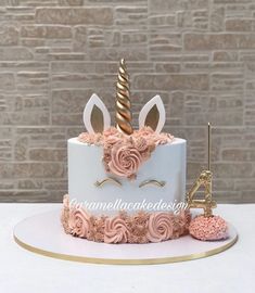 a white cake with pink frosting and a unicorn horn on top, sitting on a table