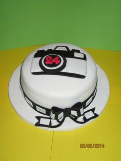 a cake with white frosting and black designs on it sitting on a yellow table