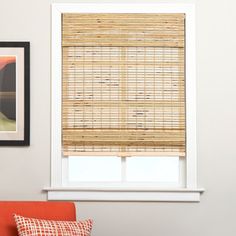 a living room with an orange chair and bamboo blinds