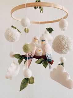 two birds are sitting on a branch and some balls hanging from the wind chime