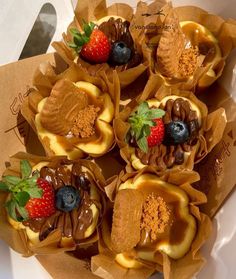 some cupcakes with chocolate and fruit in them on top of brown paper wrappers