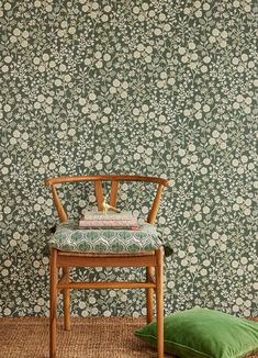 a wooden chair sitting next to a green pillow