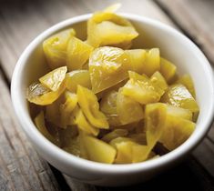 a white bowl filled with sliced pineapple on top of a wooden table