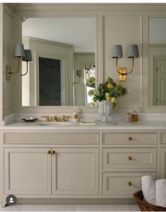 a bathroom with two sinks, mirrors and lights on the wall above them is shown