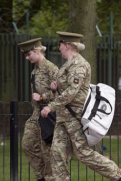 two soldiers are walking down the street carrying bags