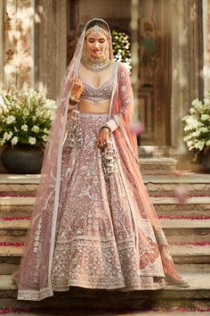 a woman in a pink lehenga standing on steps