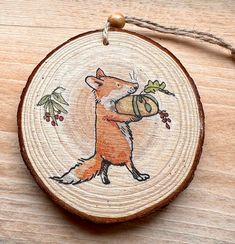 a wooden ornament with an image of a fox holding a bell on it's back