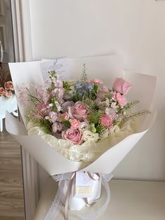 a bouquet of pink and white flowers sitting on top of a table