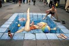 a man laying on the ground next to a painting of a woman in a swimming pool