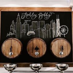 three wooden barrels sitting next to each other in front of a chalkboard with the words whiskey baby written on it