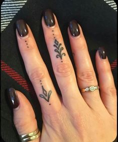 two fingers with small tattoos on them, one has a flower and the other has an arrow