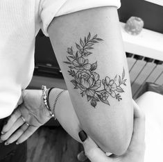 black and white photo of woman's arm with flower tattoo on the left forearm