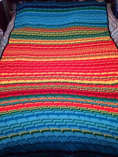 a crocheted blanket is on top of a bed