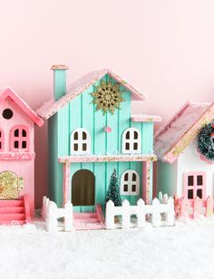 a pink and blue doll house with snow on the ground