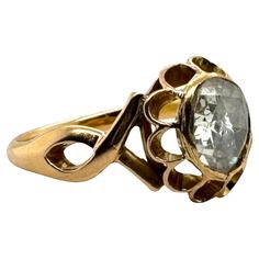 a gold ring with an oval stone in the center and two leaves on each side