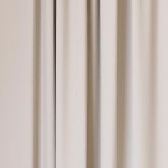 an orange vase with flowers in it sitting on a window sill next to a curtain