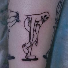 a person with a tattoo on their leg has a skeleton riding a skateboard in front of them