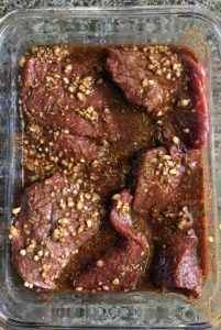 raw meat in a pan with spices and seasoning on top, ready to be cooked