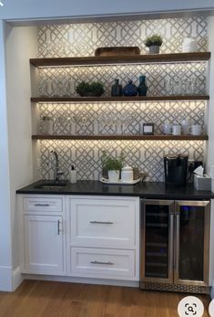 a kitchen with white cupboards and black counter tops in front of a built - in wine cooler