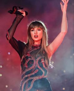 taylor swift performing on stage with her arms in the air and one hand raised above her head