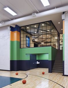 an indoor basketball court with several balls on the floor and stairs leading up to it