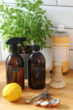 two brown bottles with lemons and cleaning supplies next to a potted plant