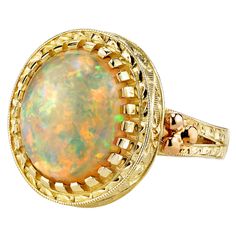 The 4.30 carat opal in this handmade 18k yellow gold ring is bursting with color! This gemstone displays flashes of bright green, orange, yellow, and the most highly-prized and rare color: red! It is difficult for photos to do this opal justice. This ring was custom-designed by our Master Jewelers in Los Angeles in order to showcase the high dome, depth of color and life in this gem. The sides of the ring have been hand engraved and show a level of artisanship and skill seldom seen today. A ring like this requires untold hours to bring to life, but will be enjoyed and treasured for years! Size 7 Complimentary sizing as needed Gem Ring, 18k Yellow Gold Ring, Domed Ring, Gems Jewelry, Yellow Gold Ring, Gem Stone, Hand Engraving, Bright Green, Yellow Gold Rings