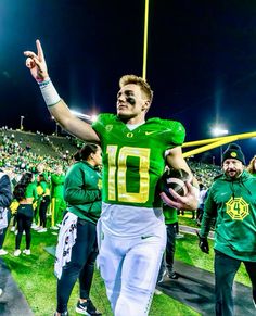 a football player walking onto the field with his arms in the air