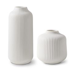 two white vases sitting next to each other on a white surface with no one around them