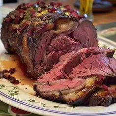 a piece of roast beef on a plate with potatoes and garnishes around it