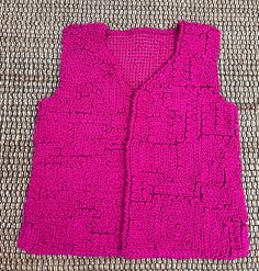 a crocheted pink vest sitting on top of a couch