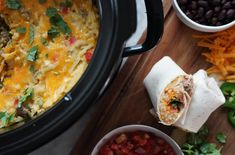 a crock pot filled with mexican food next to bowls of beans and tortillas