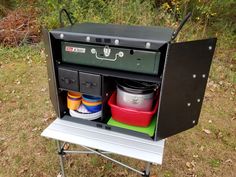 an outdoor cooking station with pots and pans on the top, sitting in grass