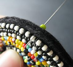 a person is stitching beads on to a piece of black material with a needle