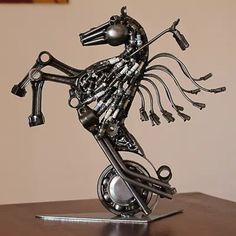 a metal horse sculpture sitting on top of a wooden table