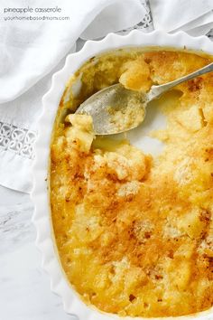 a casserole dish with a spoon in it on a lace doily and white napkin