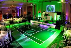 an indoor tennis court is lit up with purple and green lighting for a wedding reception